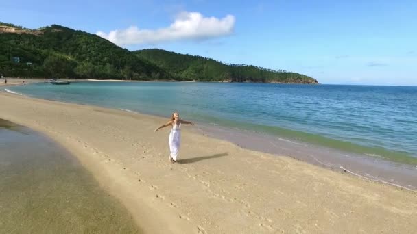 Gelukkig vrije vrouw in witte jurk draait op zand spuug op Paradise Beach. Luchtfoto. — Stockvideo