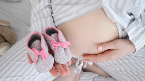 Baby Shoes In The Hands Of A Future Mother. Těhotné břicho Closeup. — Stock video