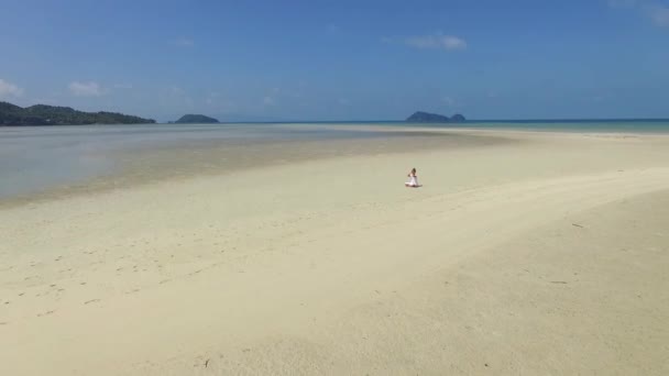 Вид с воздуха: женщина-йог медитирует на пляже тропического острова — стоковое видео