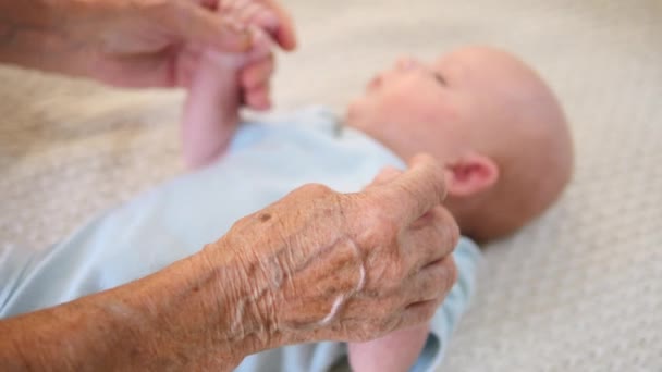 Ruce staré babičky držící dítě za ruce. Closeup.