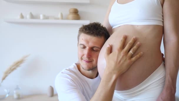 Joven futuro padre abrazando y besos vientre de su embarazada esposa . — Vídeo de stock
