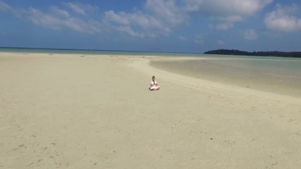 Een vrouw die yoga en meditatie doet op het strand. Luchtfoto. — Stockvideo