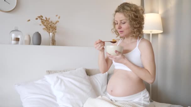 Mujer embarazada tomando cereales para desayunar en la cama. Concepto de la dieta del embarazo . — Vídeos de Stock