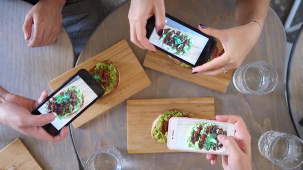 Grupp av vänner som tar foto av mat tillsammans med hjälp av mobiltelefoner. — Stockvideo