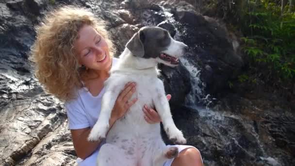 Gelukkig vrouw met haar huisdier hond in bos bij waterval — Stockvideo