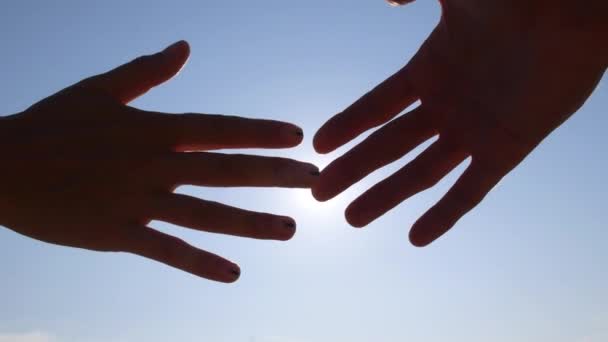 Θηλυκά και αρσενικά χέρια που αγγίζουν με άκρες δακτύλων ενάντια στον ήλιο στο μπλε ουρανό — Αρχείο Βίντεο