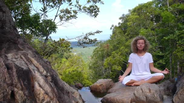 Hermosa mujer haciendo meditación y yoga en la naturaleza en la cascada — Vídeos de Stock