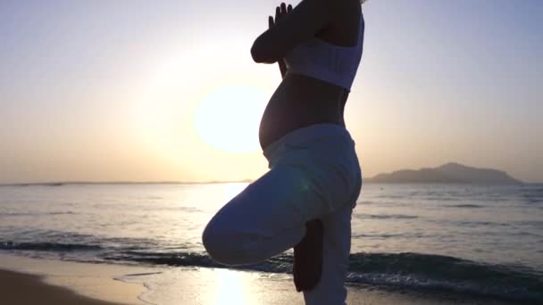 Gravid kvinna som gör yoga på stranden vid soluppgången. — Stockvideo