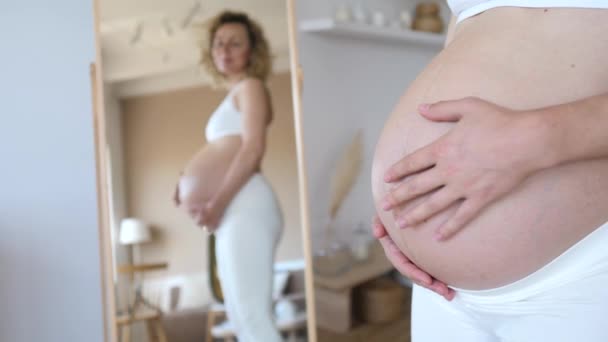 Sorrindo Mulher grávida olhando para espelho segurando sua barriga . — Vídeo de Stock