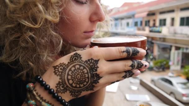 Молодая женщина чувствует запах горячей чашки кофе в кафе — стоковое видео