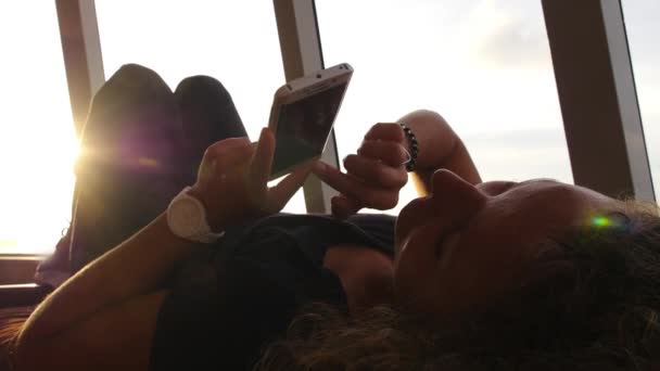 Женщина с помощью мобильного телефона расслабляется на диване — стоковое видео
