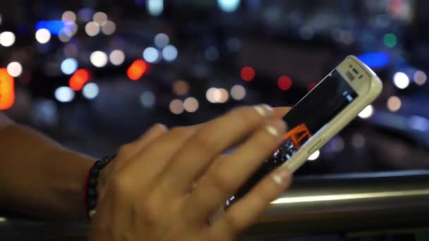 Usar el teléfono celular al aire libre con tráfico nocturno desenfocado — Vídeo de stock