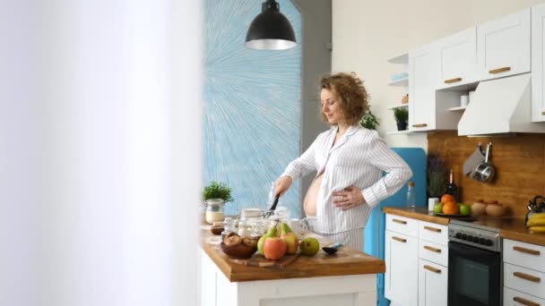 Szczęśliwa koncepcja zdrowej ciąży. Ciężarna kobieta pieczenia na kuchni. — Wideo stockowe
