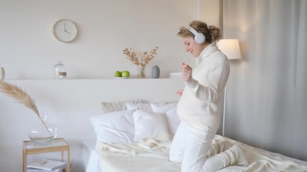 Heureuse femme enceinte souriante à la maison dansant au lit — Video
