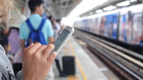 Frau benutzt Smartphone auf Bahnsteig und wartet auf Zug — Stockvideo