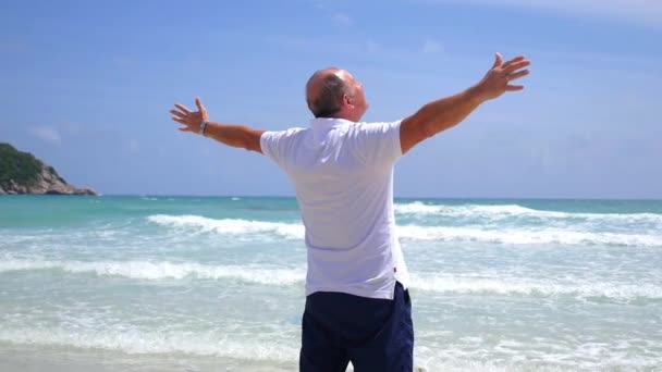 Snygg, vuxen man som sträcker ut armarna på stranden — Stockvideo