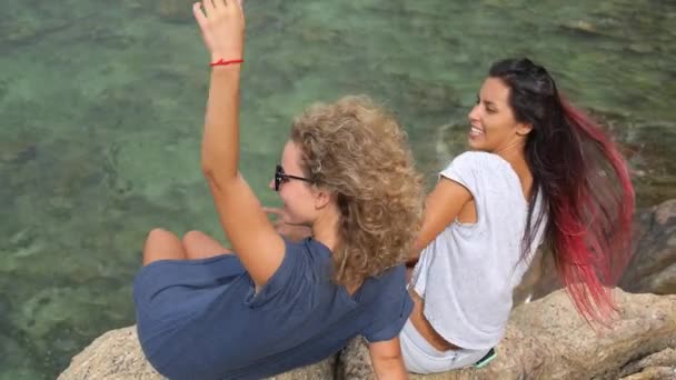 Jonge vrouwen vrienden zitten aan de zee — Stockvideo