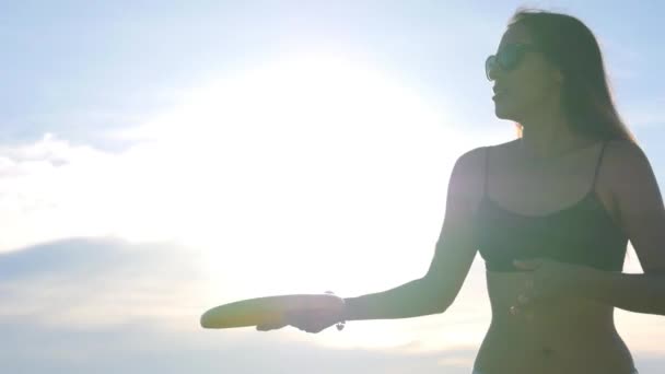 Jonge sexy vrouw speelt frisbee op het strand. Langzame beweging. — Stockvideo