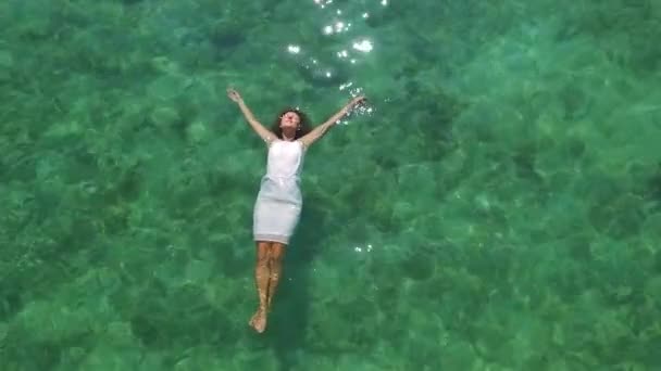 Bovenste luchtfoto. Jonge vrouw in witte jurk zwemmen in turquoise zee. — Stockvideo