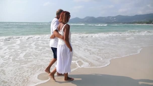 Pareja de mediana edad caminando en la playa. Moción lenta . — Vídeo de stock