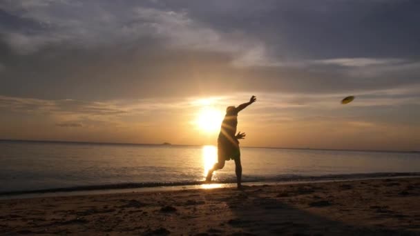 Män som leker frisbee på stranden vid solnedgången — Stockvideo