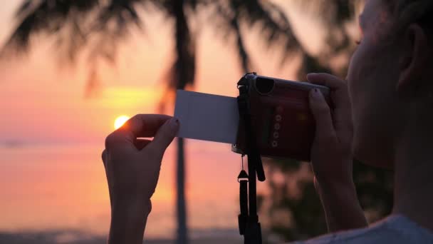 日没時にレトロポラロイドカメラで写真を撮る女 — ストック動画