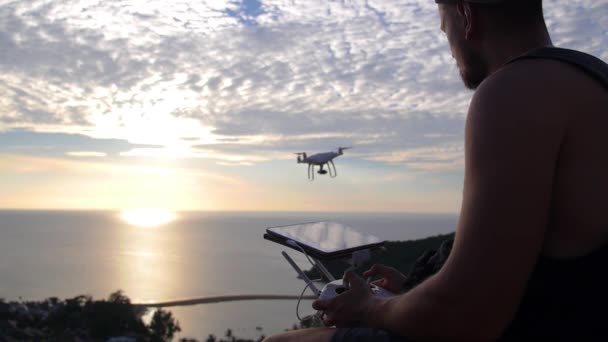 Mann setzt Drohne bei Sonnenuntergang über dem Meer ein — Stockvideo