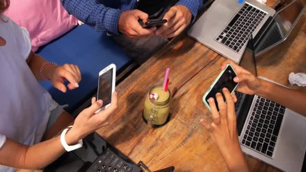 Fiatal emberek csoportja okostelefonnal és laptoppal a Cafe-ban. Indítás vagy csapatmunka koncepciója. — Stock videók