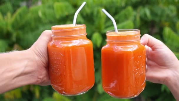 Duas mãos com suco de cenoura saudável em jarra de vidro — Vídeo de Stock