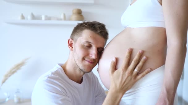 Homem feliz beijando barriga de sua esposa grávida . — Vídeo de Stock