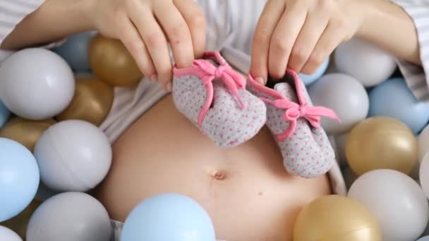 Donna incinta che gioca con Stivaletti per il suo futuro bambino. Primo piano . — Video Stock