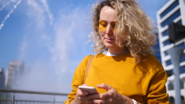 Jeune fille élégante utilisant un téléphone portable en ville en plein air . — Video