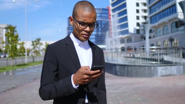 Genç işadamı cep telefonuyla şehirde — Stok video