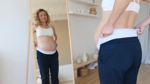 Anyaruha-koncepció. Terhes nő terhességi nadrágot visel. — Stock videók
