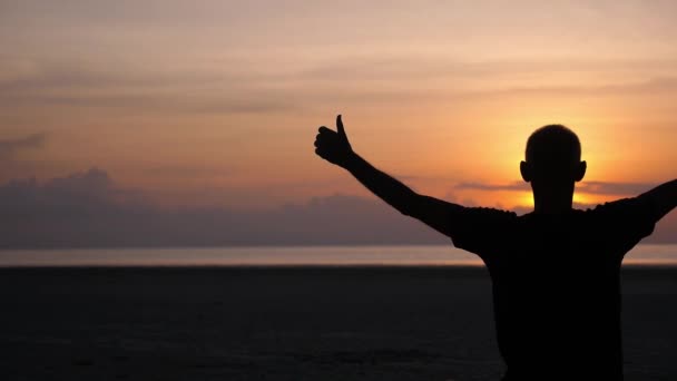 Hombre Yogui meditando al atardecer y animando al sol en la playa — Vídeo de stock