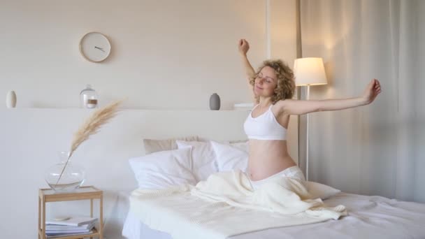 Glad graviditetskoncept. Gravid kvinna Stretching i sängen hemma. — Stockvideo