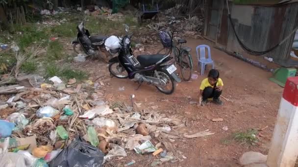Маленькая девочка играет с мусором на улице в азиатских трущобах Камбоджи . — стоковое видео