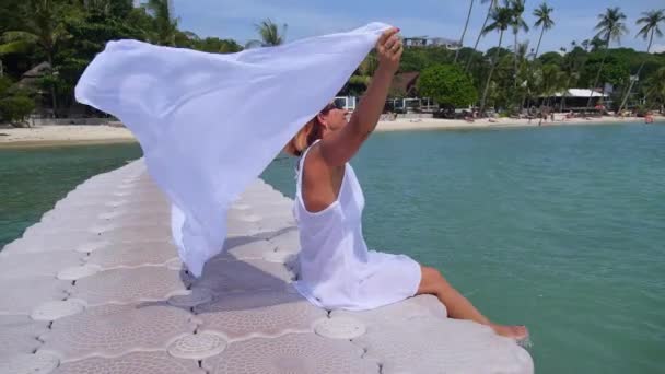 Mujer mayor en vestido blanco tomando el sol en la playa por el mar. Moción lenta . — Vídeo de stock