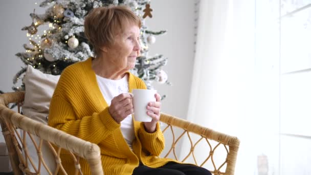 Senior grootmoeder ontspannen thuis met kopje koffie in de kersttijd. — Stockvideo