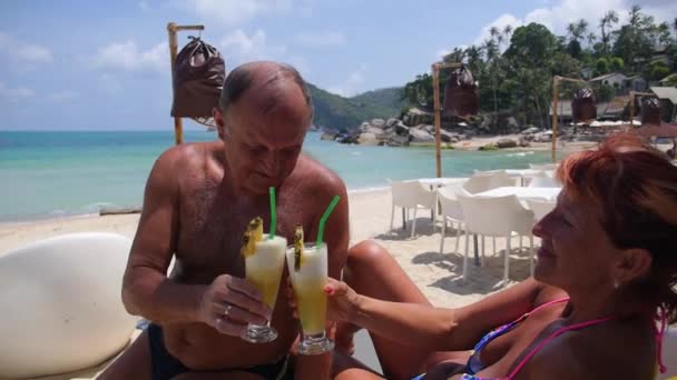 Feliz pareja de personas mayores bebiendo cóctel exótico en la playa tropical — Vídeo de stock