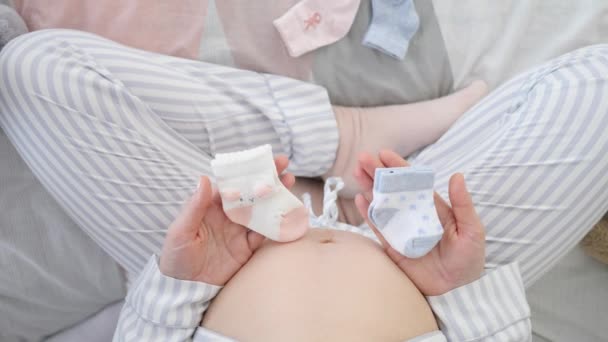 Беременная женщина с детскими носками, ожидающая близнецов — стоковое видео
