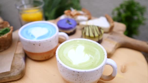 茶杯中的绿茶拿铁和蓝茶拿铁放在桌上. — 图库视频影像