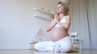 Namaste Mudra 'da elleri ile meditasyon yapan mutlu hamile kız evde yoga yapıyor..
