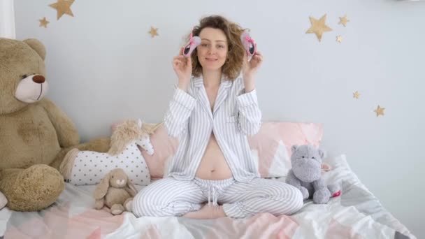 Glücklich schwangere Frau spielt mit kleinen Schuhen für ihr zukünftiges Baby im Bett — Stockvideo