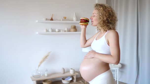 Feliz jovem grávida mulher segurando hambúrguer . — Vídeo de Stock