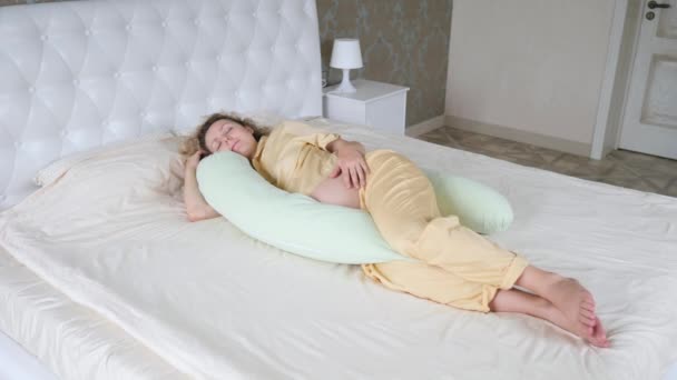 Glad graviditetskoncept. Gravid kvinna sover med moderskap kudde i sovrummet. — Stockvideo