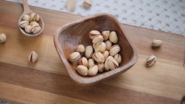 Drewniana miska z pistacjami na drewnianej desce. — Wideo stockowe