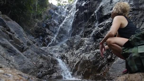 Junge Frau nach Wanderung mit Rucksack am Wasserfall — Stockvideo