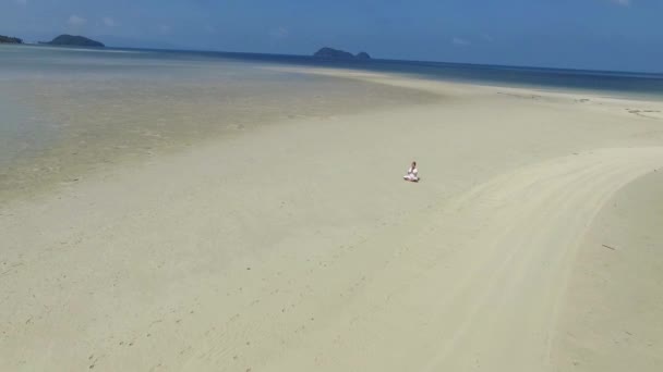 Vista aérea: meditación de la mujer del yoga en la playa blanca por el mar — Vídeo de stock