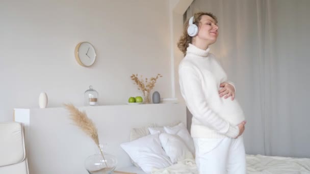 Giovane donna incinta sorridente che balla a casa. Stile di vita felice e concetto di gravidanza . — Video Stock